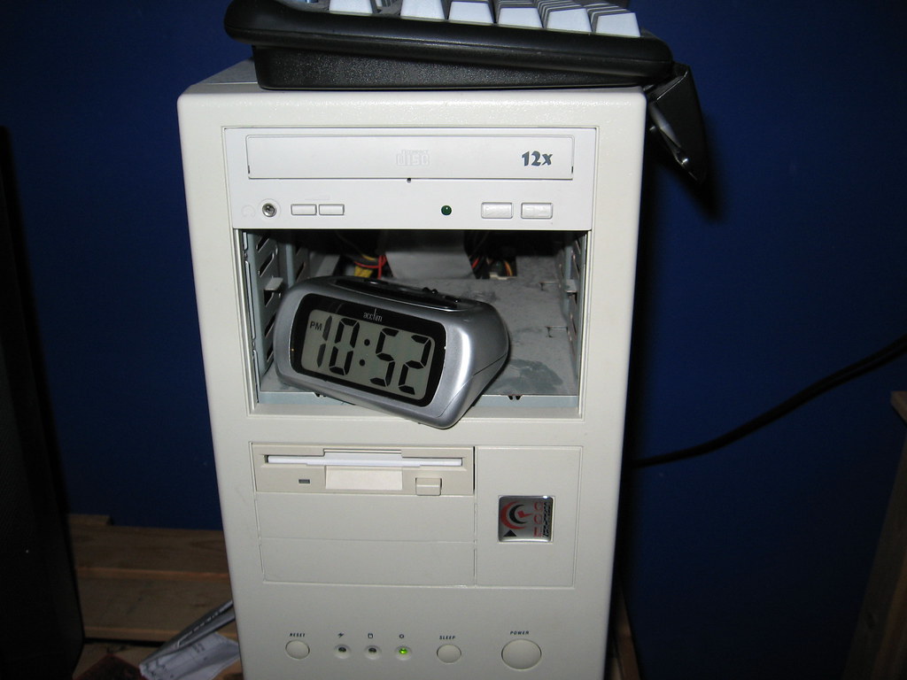 Ein Wecker auf einem PC-Gehäuse — Sinnbild für zeitgesteuerte Automatisierung